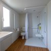 Bagno con doccia accessibile e pavimento in legno.