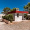Piccola casa bianca con tetto rosso e mobili da giardino.