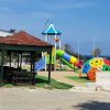 Parco giochi con scivolo, altalene e gazebo in legno.