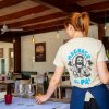 Cameriera in ristorante con bicchieri e tavoli apparecchiati.