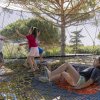 Bambini giocano su una rete sospesa tra gli alberi.