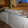 Tavolo con tovaglia decorata, fiori e scatole regalo disposte in fila.