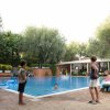 Bambini giocano in una piscina circondata da alberi.