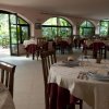Ristorante con tavoli apparecchiati vicino a finestre ampie.
