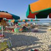 Spiaggia con ombrelloni e lettini colorati.