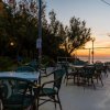 Terrazza all'aperto al tramonto, tavoli vuoti e alberi sullo sfondo.