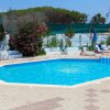 Piscina di forma irregolare con lettini e ombrelloni, circondata da vegetazione.