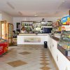 Interno di un bar con bancone fornito di bevande e un congelatore Algida.
