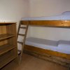 Letto a castello in legno con scala, accanto a una libreria vuota in una stanza.