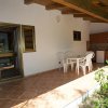 Veranda con tavolo e sedie in plastica, affacciata su un giardino, con angolo cottura.