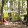 Due persone sedute accanto a una tenda in un campeggio, con biciclette e decorazioni colorate.