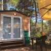 Una casetta in legno con veranda, ombrellone e sedia all'aperto.