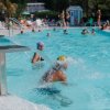 Piscina estiva affollata con persone che si rinfrescano.