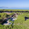 Vista dall'alto di una zona verde con alberi e il mare sullo sfondo.