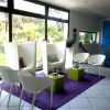 Sala moderna con sedie bianche, divani alti e tappeto viola.