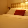 Letto con cuscino arancione, testiera a quadri beige e lampade soffuse.