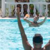 Due persone giocano a palla in una piscina azzurra.