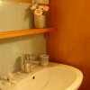 Lavabo con specchio e fiori in vaso su mensola.