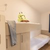 Stanza con letto a castello, zaino e jeans sul letto superiore.
