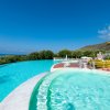 Piscina a sfioro con terrazza e mare sullo sfondo.