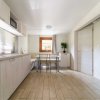 Cucina moderna con mobili in legno chiaro, tavolo con sedie e una finestra che illumina la stanza.