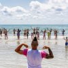 Persone fanno esercizi in mare sotto il sole.